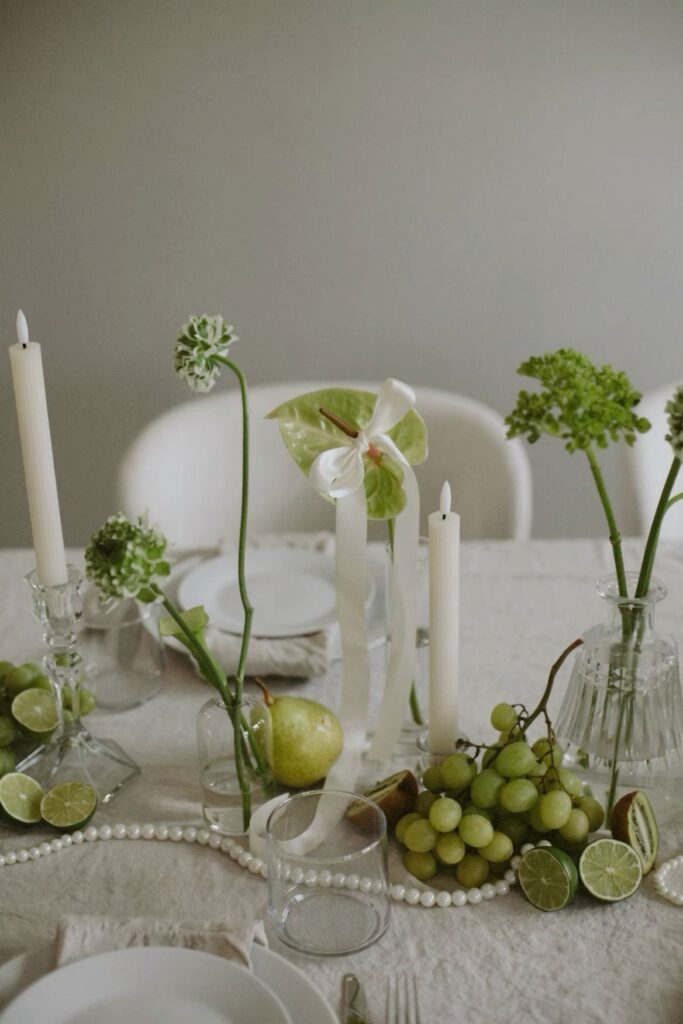 Mesa con diseño biofílico: macetas con hierbas aromáticas, centro de hojas verdes y vajilla en tonos tierra.