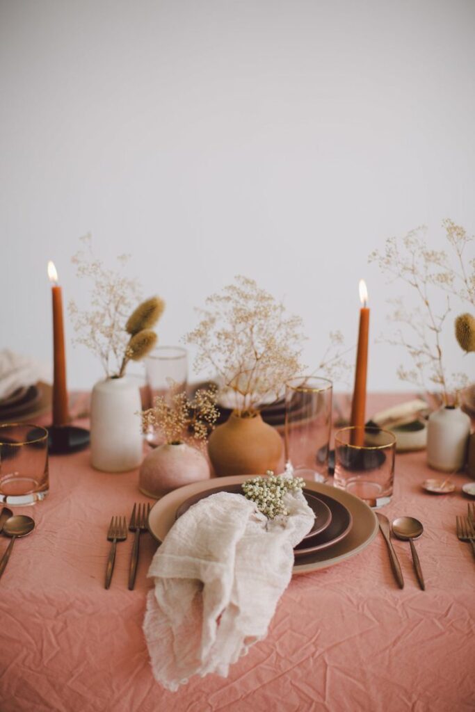 Mesa decorada con vajilla artesanal de cerámica reciclada, servilletas de lino y centro natural con flores secas.
